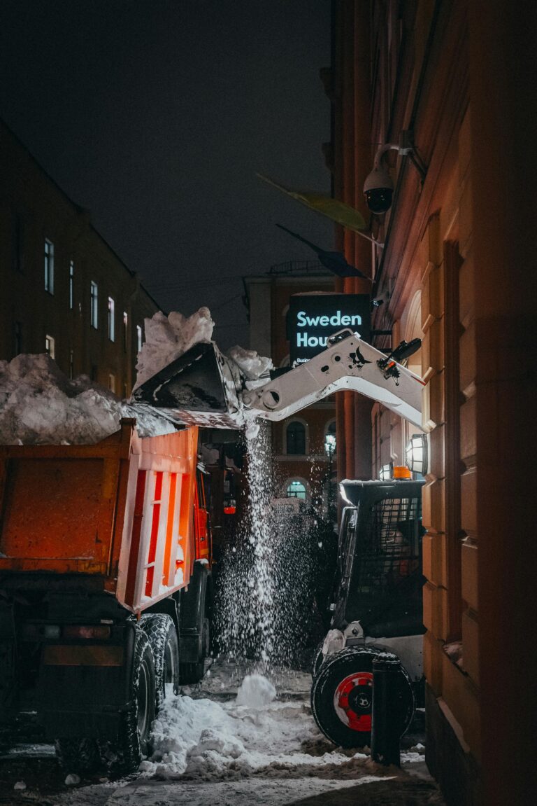 Night scene of snow removal using a truck and skid steer near Sweden House.